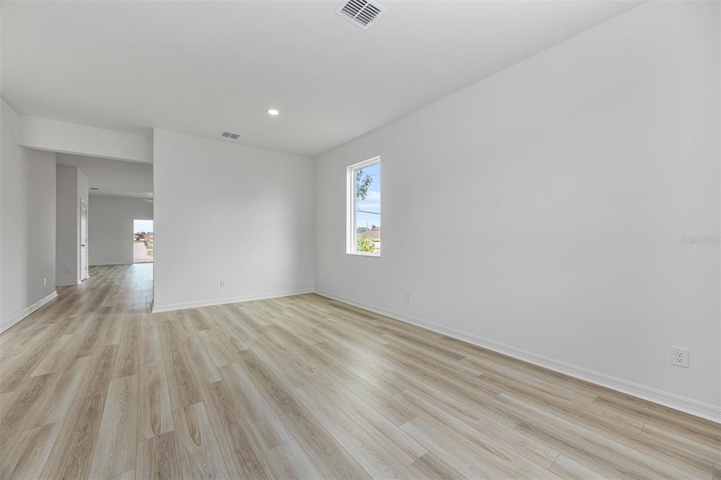 An empty room features light wood-look flooring, white walls, and a single window — 247 BIG SIOUX DRIVE, POINCIANA, FL
