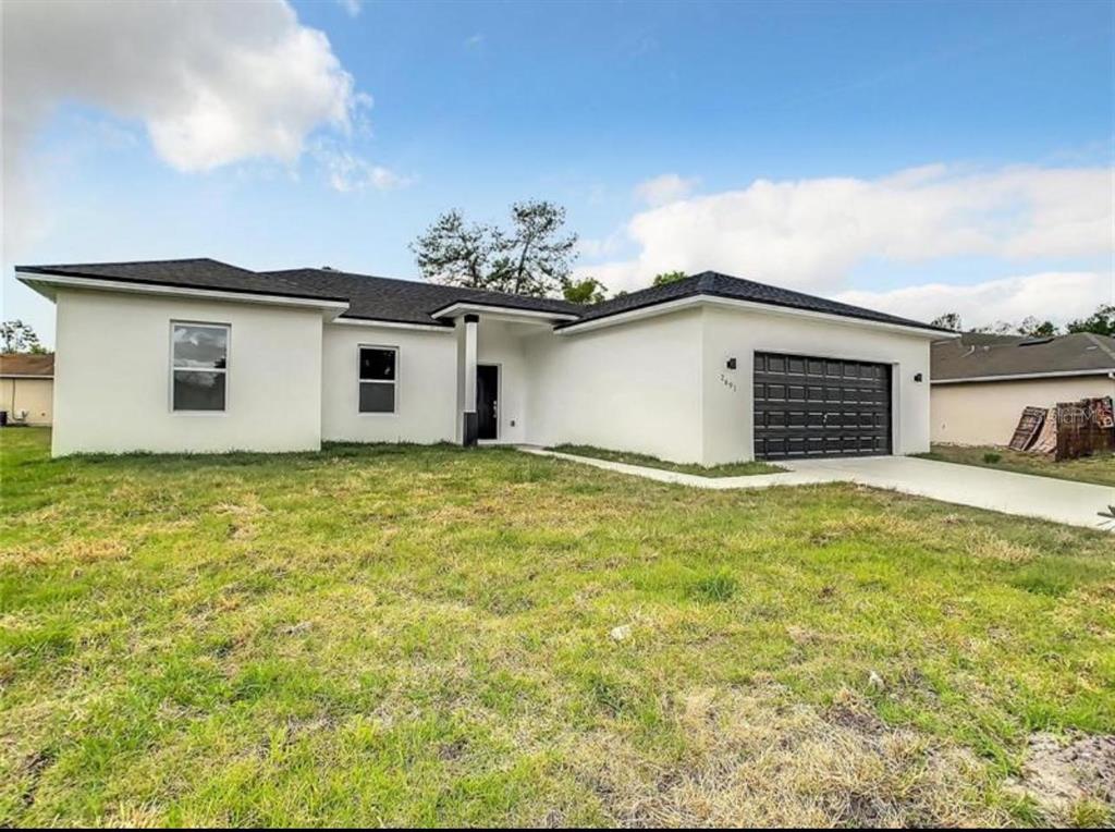 A single-story house with white stucco walls, a dark roof, and a two-car garage — 17000 SW 41ST COURT, OCALA, FL