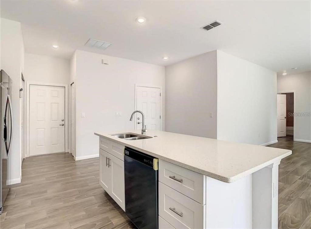 A kitchen island with a sink and dishwasher sits in a room with light flooring — 17000 SW 41ST COURT, OCALA, FL