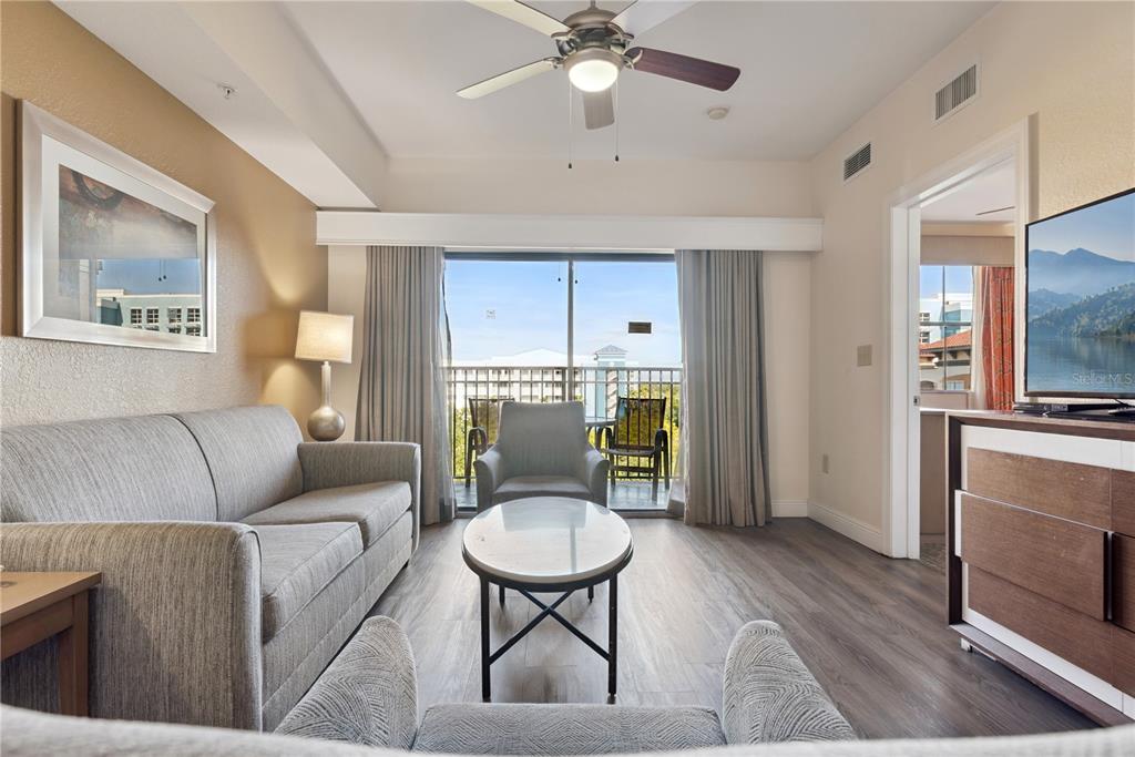 A living room features a gray sofa, armchairs, a coffee table, and a balcony view — 12538 FLORIDAYS RESORT DRIVE UNIT 602C, ORLANDO, FL