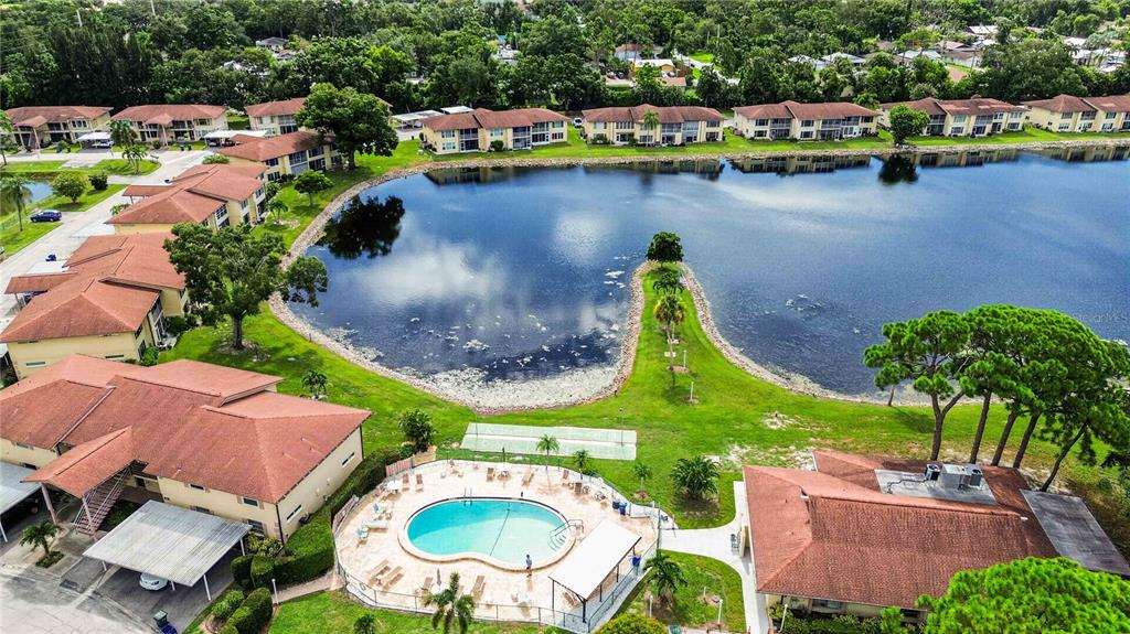 An aerial view shows a residential complex with a swimming pool beside a large lake — 4565 TIPPECANOE TRAIL UNIT 22, SARASOTA, FL