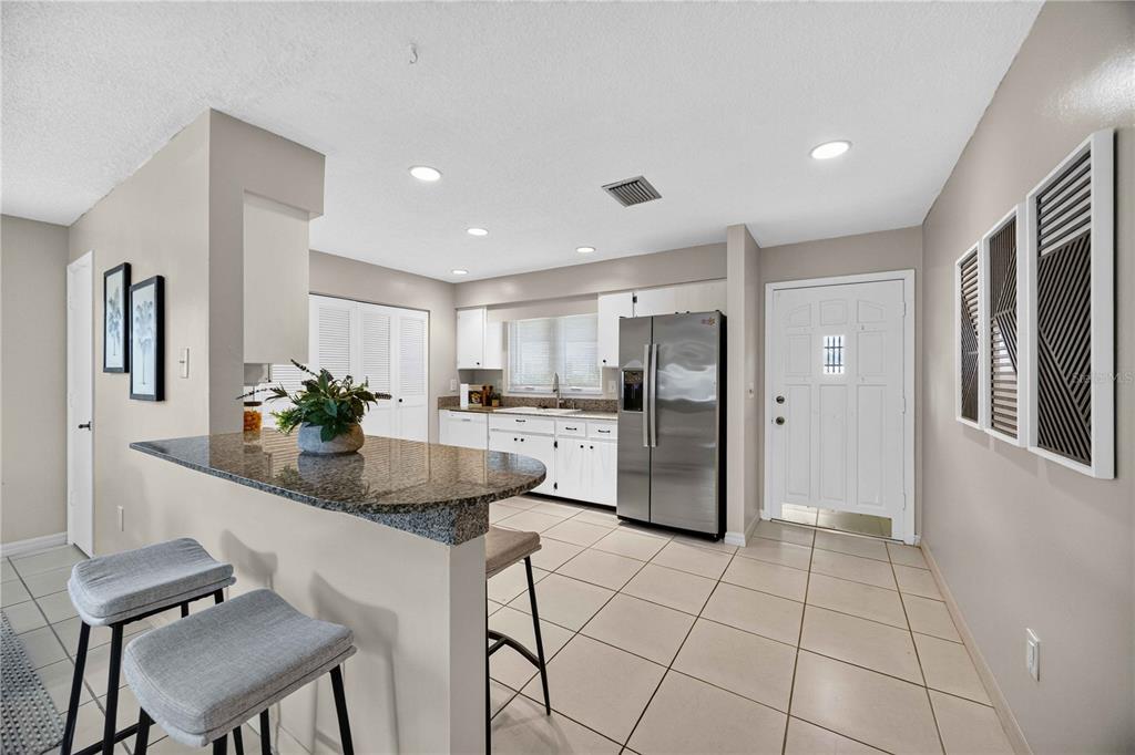 A kitchen features white cabinets, stainless steel appliances, a granite breakfast bar, and tiled flooring — 4565 TIPPECANOE TRAIL UNIT 22, SARASOTA, FL
