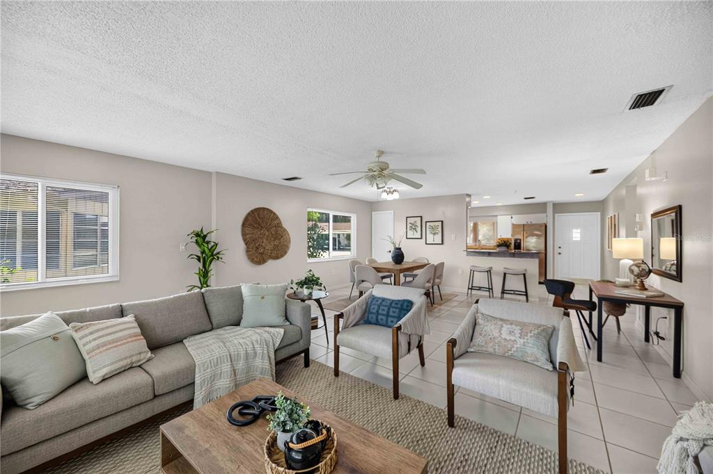 An open-concept living and dining area features light tile flooring, neutral walls, and modern furniture — 4565 TIPPECANOE TRAIL UNIT 22, SARASOTA, FL