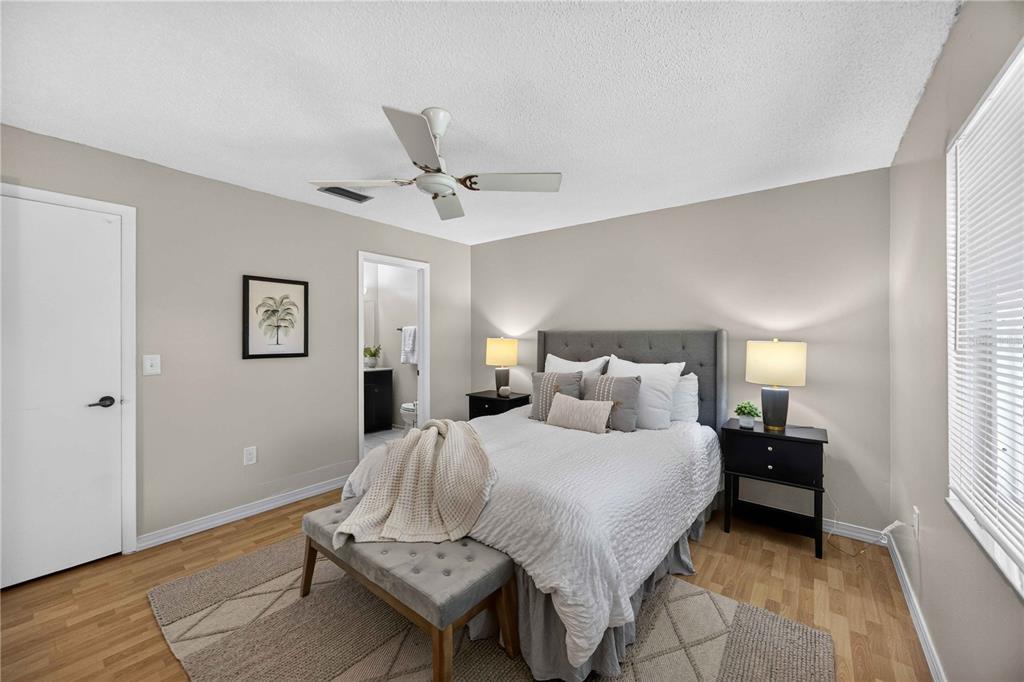A bedroom features a gray upholstered bed, two black nightstands, and light wood-look flooring — 4565 TIPPECANOE TRAIL UNIT 22, SARASOTA, FL
