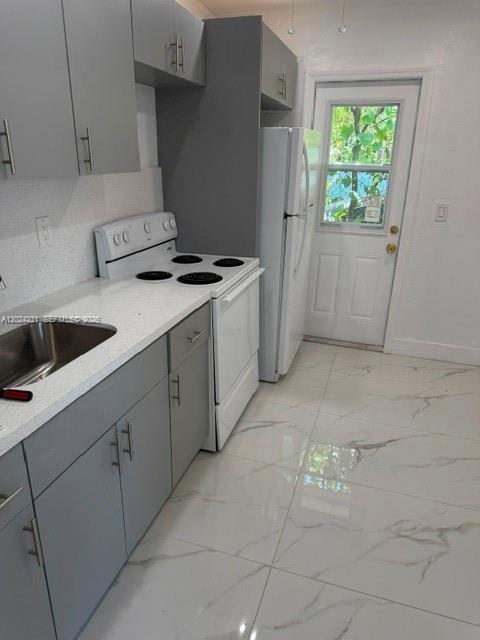 A small bathroom features white marble-patterned wall and floor tiles, a toilet, and a shower — 262 NE 55th Ter # 0, Miami FL 33137, MIAMI, FL