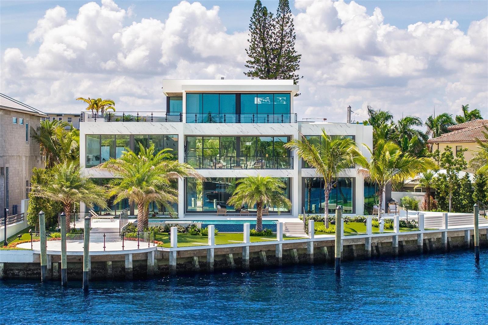 A modern three-story waterfront home with floor-to-ceiling windows, a pool, and palm trees — 1555 SE 14th Court, Deerfield Beach FL 33441, DEERFIELD BEACH, FL