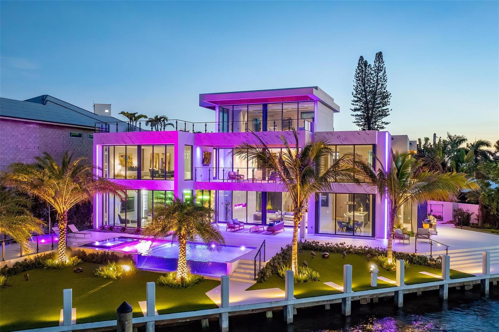 A modern three-story waterfront mansion with a pool, glass walls, and purple accent lighting — 1555 SE 14th Court, Deerfield Beach FL 33441, DEERFIELD BEACH, FL