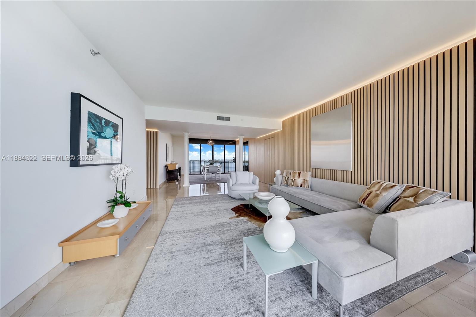 A modern living room features a large sectional sofa, wood-slat wall paneling, and balcony views — 1000 Venetian Way # 1902, Miami FL 33139, MIAMI, FL
