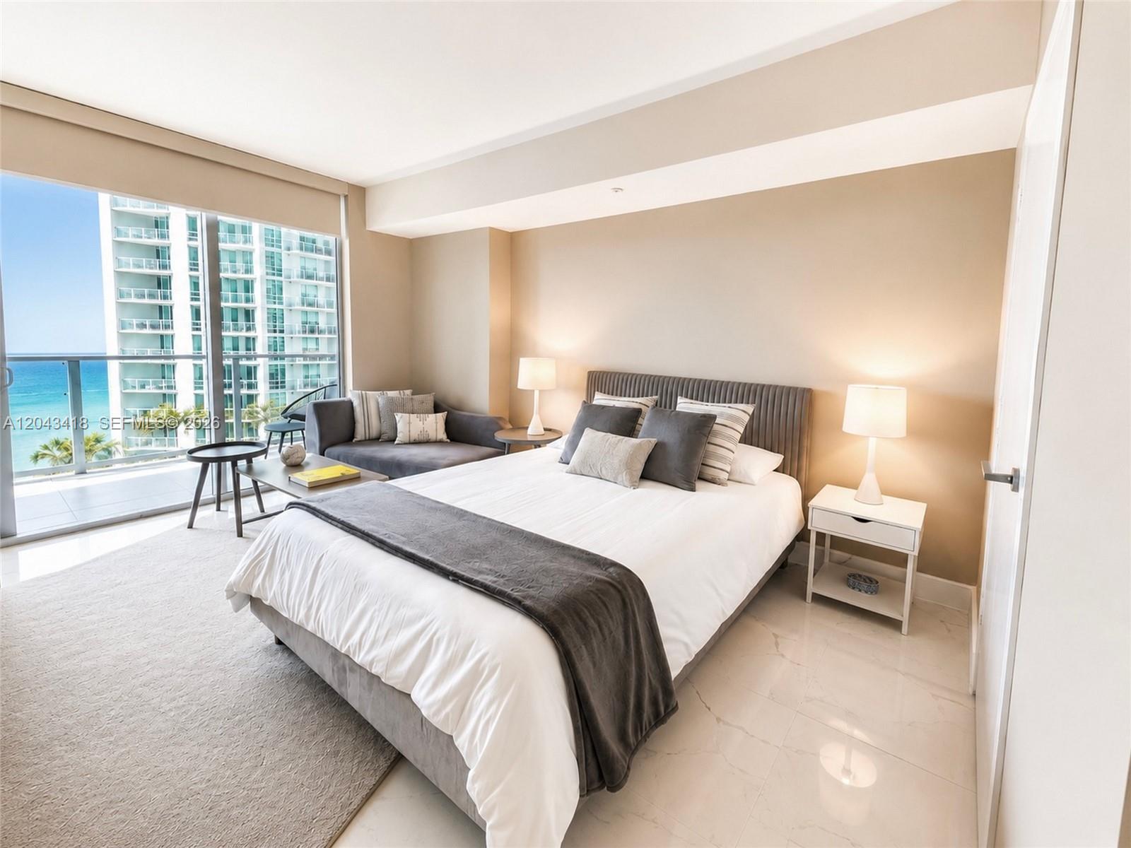 A bedroom features a bed, a small sofa, and a balcony overlooking the ocean — 1300 Brickell Bay Dr # 1806, Miami FL 33131, MIAMI, FL