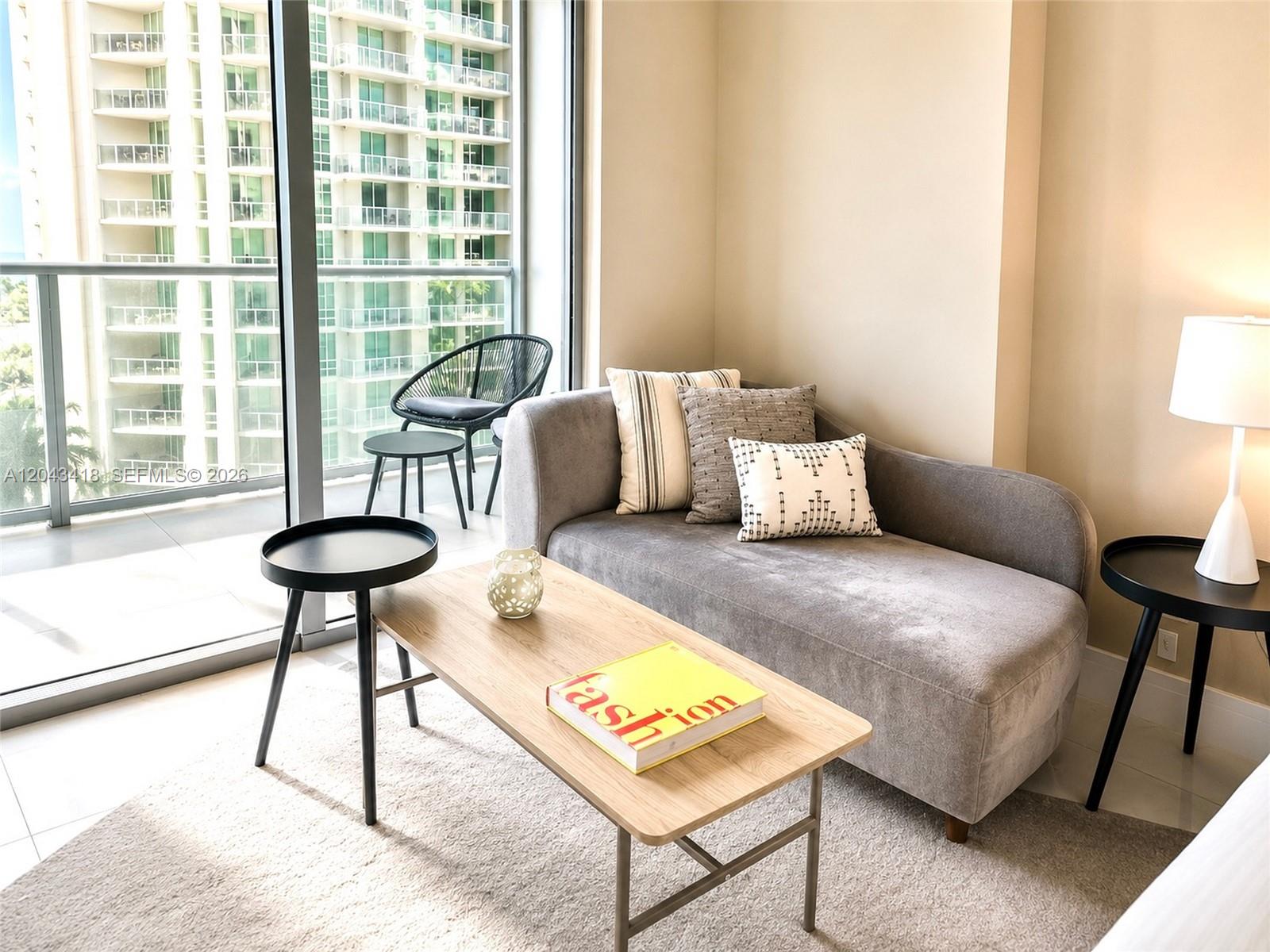 A gray chaise lounge sits in a room with a coffee table and balcony view — 1300 Brickell Bay Dr # 1806, Miami FL 33131, MIAMI, FL