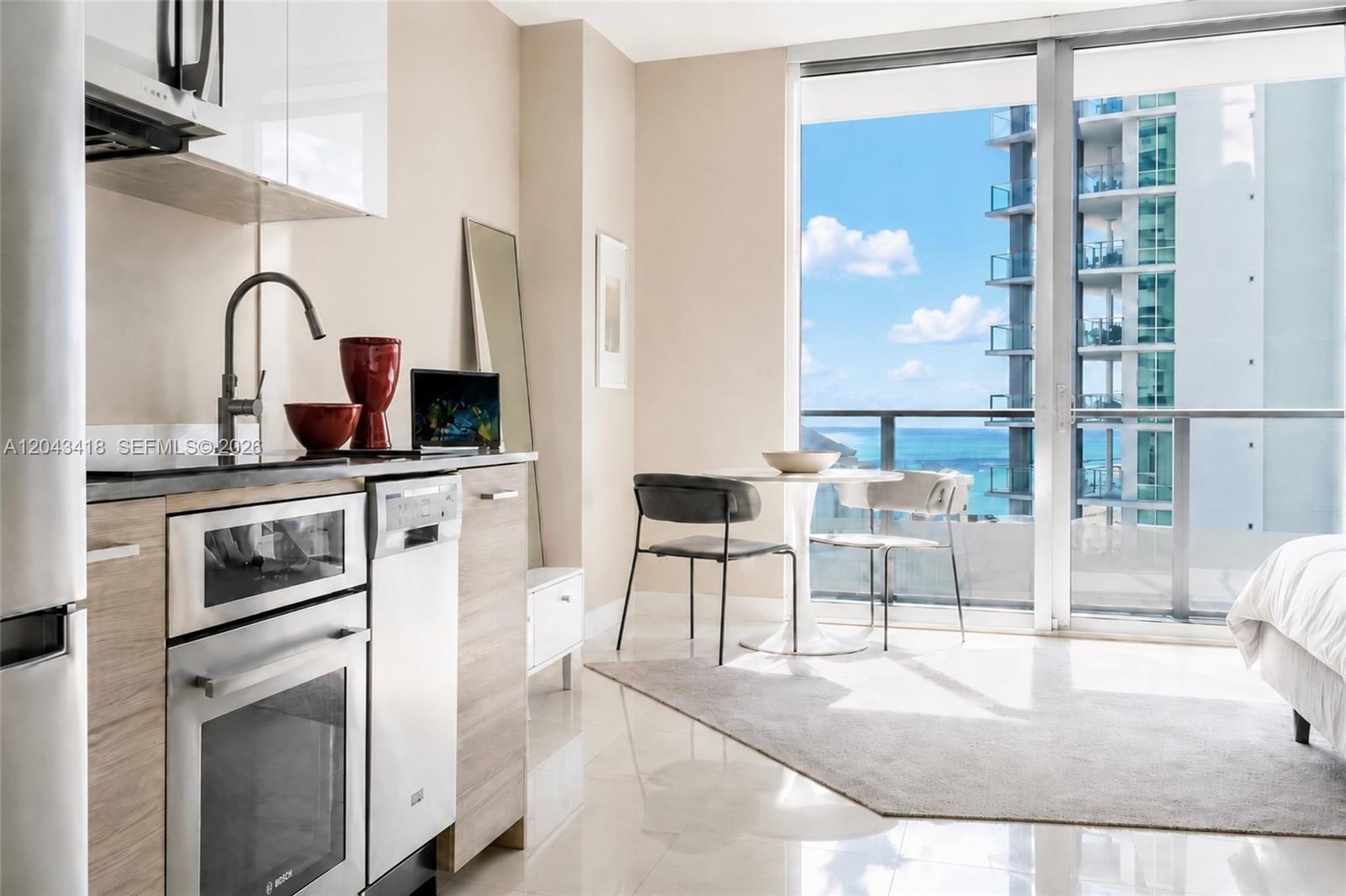 A studio apartment kitchen and dining area with floor-to-ceiling windows overlooking the ocean — 1300 Brickell Bay Dr # 1806, Miami FL 33131, MIAMI, FL