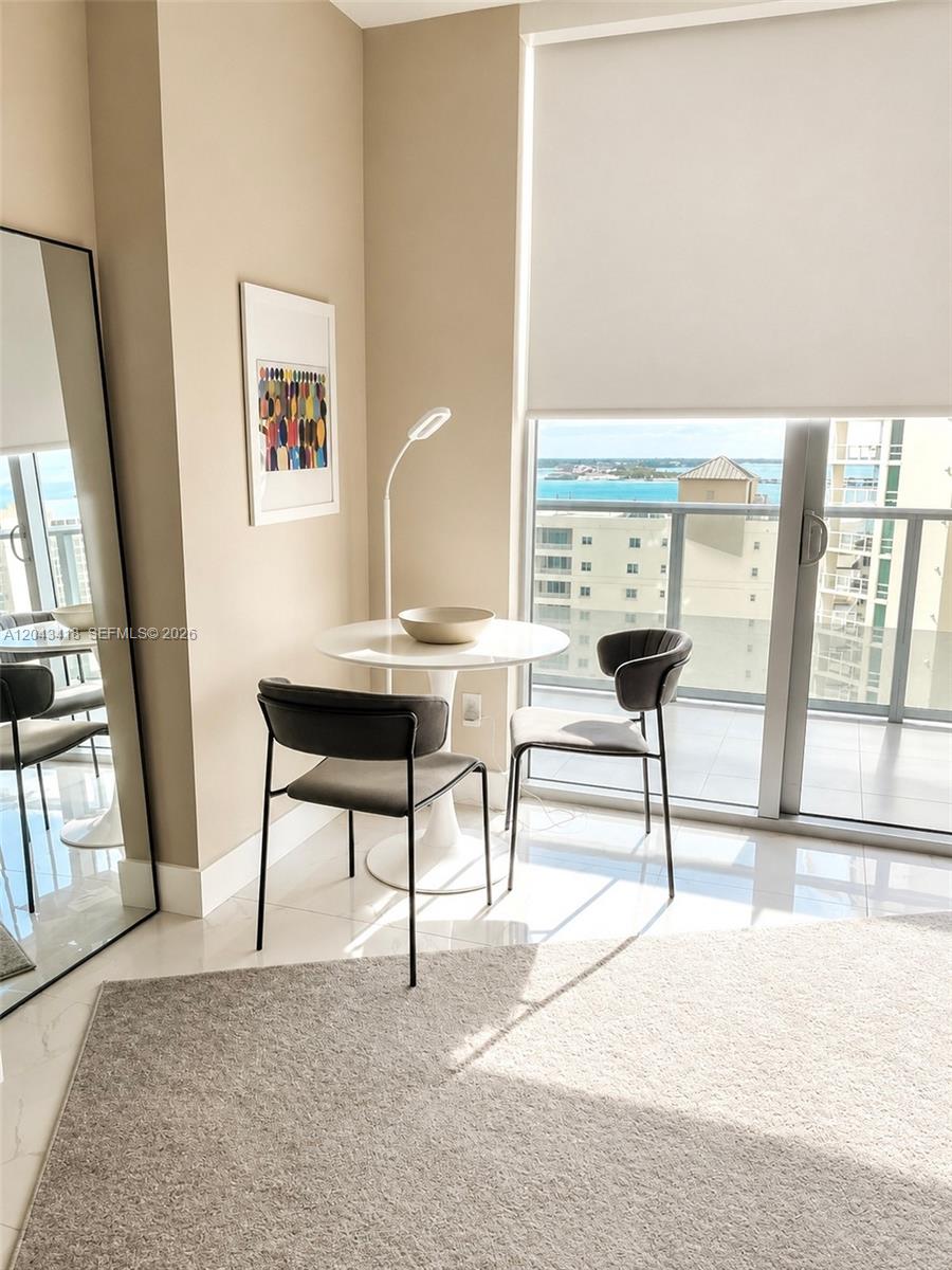 A small dining area features a white pedestal table, two dark chairs, and floor-to-ceiling windows — 1300 Brickell Bay Dr # 1806, Miami FL 33131, MIAMI, FL