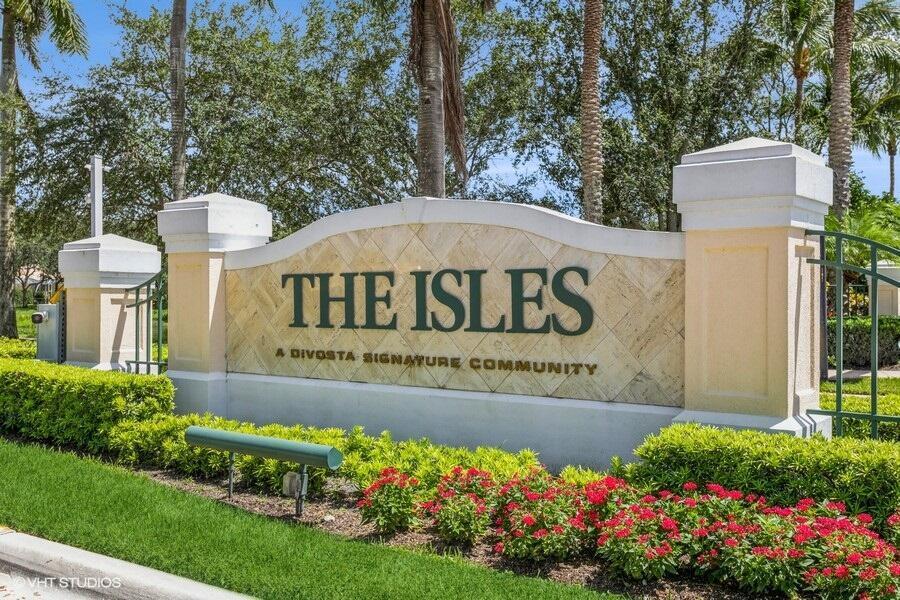 A stone monument sign for The Isles community stands behind a bed of red flowers — 170 Euphrates Circle, Palm Beach Gardens FL 33410, PALM BEACH GARDENS, FL