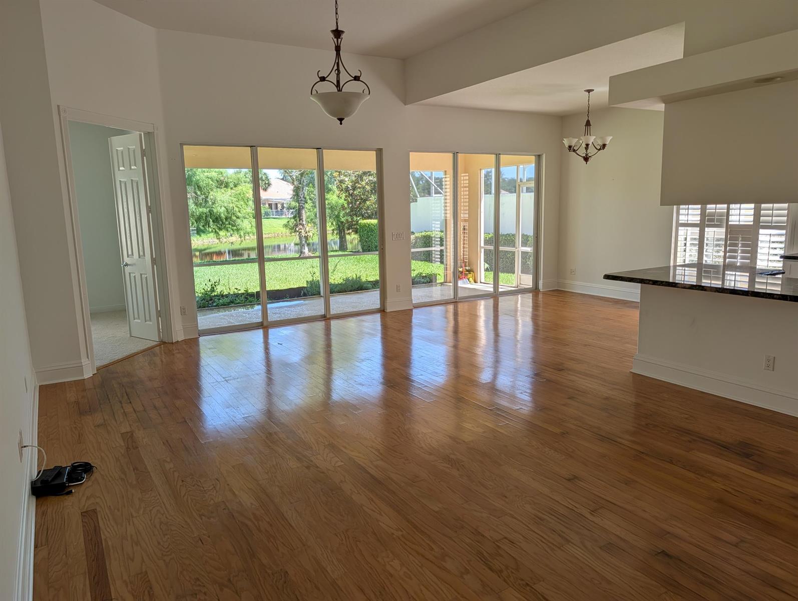 An open-concept living area features hardwood floors, large sliding glass doors, and a kitchen island — 170 Euphrates Circle, Palm Beach Gardens FL 33410, PALM BEACH GARDENS, FL