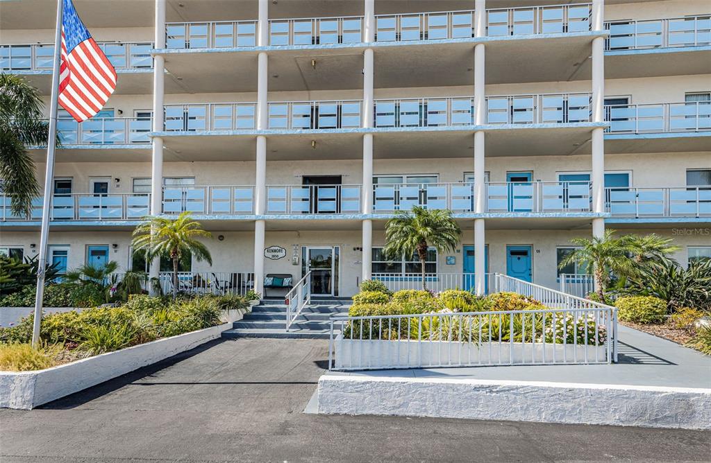 A multi-story apartment building features a central entrance, balconies, and a paved parking area — 2850 59TH STREET S UNIT 204, GULFPORT, FL