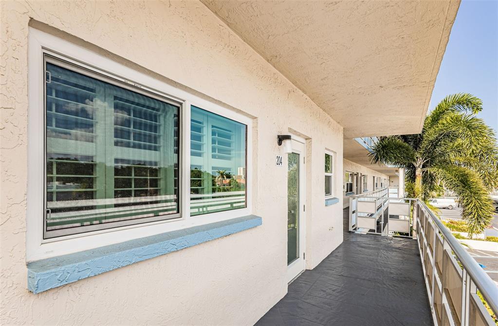 An exterior walkway leads to the entrance of unit 204, featuring a window and railing — 2850 59TH STREET S UNIT 204, GULFPORT, FL
