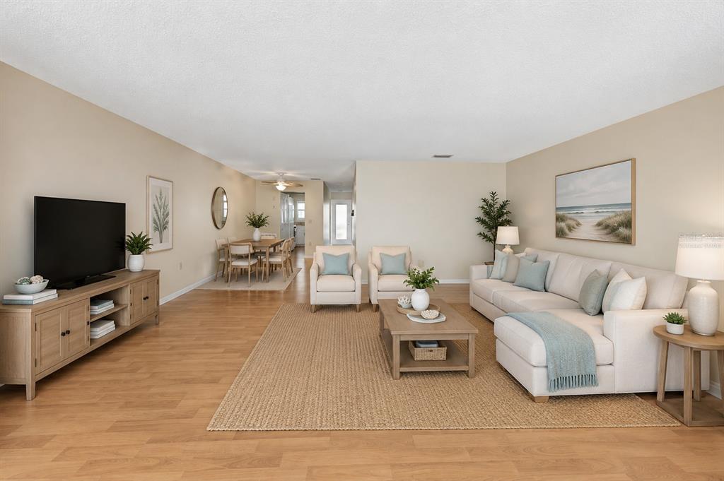 A bright living room features light wood floors, a neutral sofa, and a dining area — 2850 59TH STREET S UNIT 204, GULFPORT, FL