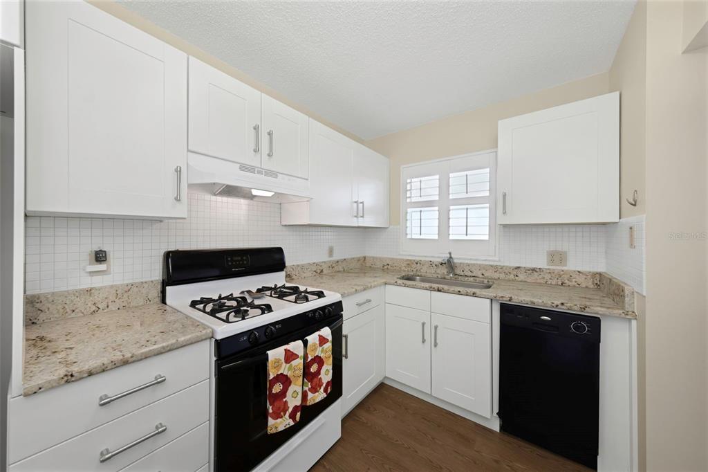 A kitchen features white cabinets, granite countertops, a black stove, and a black dishwasher — 2850 59TH STREET S UNIT 204, GULFPORT, FL