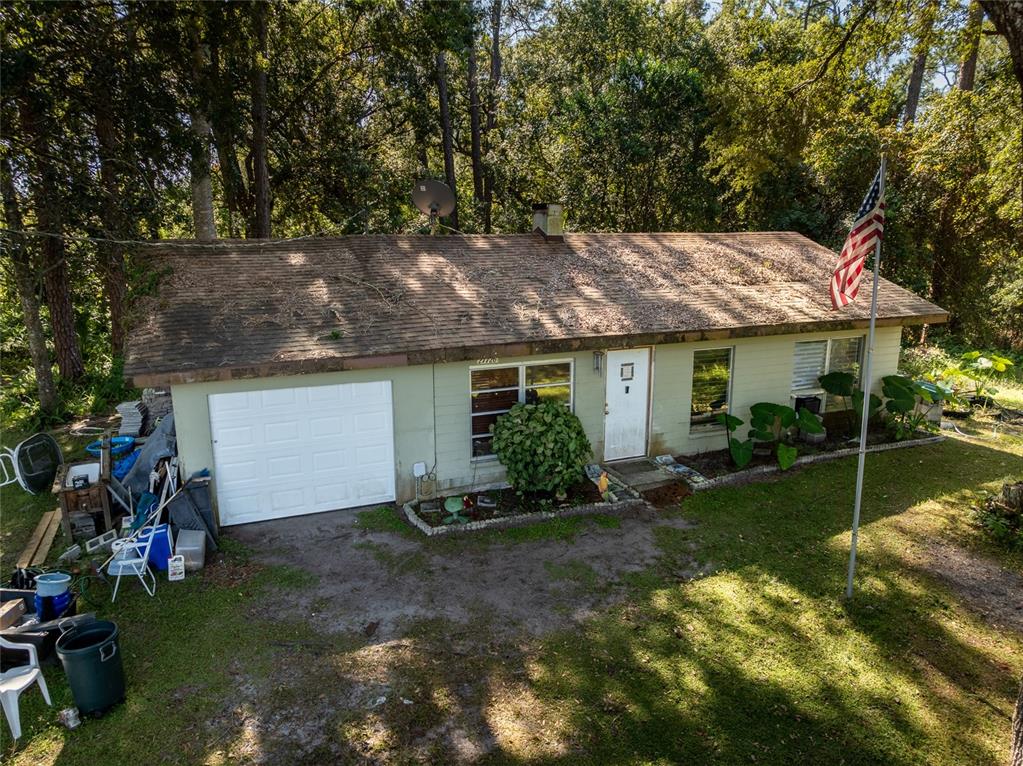 An aerial view of a single-story house with a garage, light siding, and a flag — 27726 LUELLA AVENUE, PAISLEY, FL