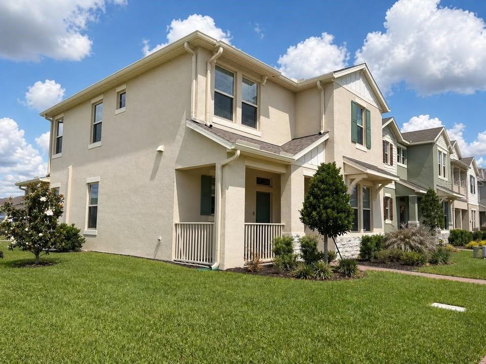 A two-story tan stucco townhouse with a front porch and a green lawn — 10042 SWAY STREET, WINTER GARDEN, FL