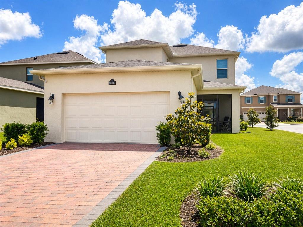 A two-story stucco house features a two-car garage and a paved driveway — 10042 SWAY STREET, WINTER GARDEN, FL