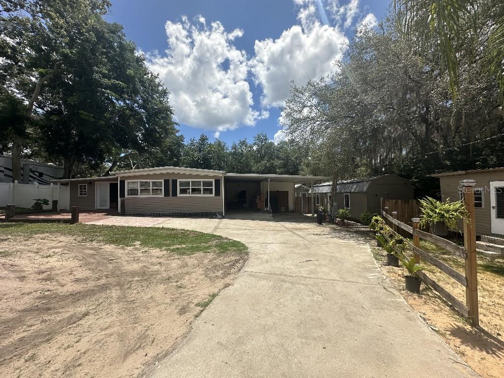 A single-story house with a carport, concrete driveway, and a small adjacent structure — 16975 SE 249TH AVENUE, UMATILLA, FL