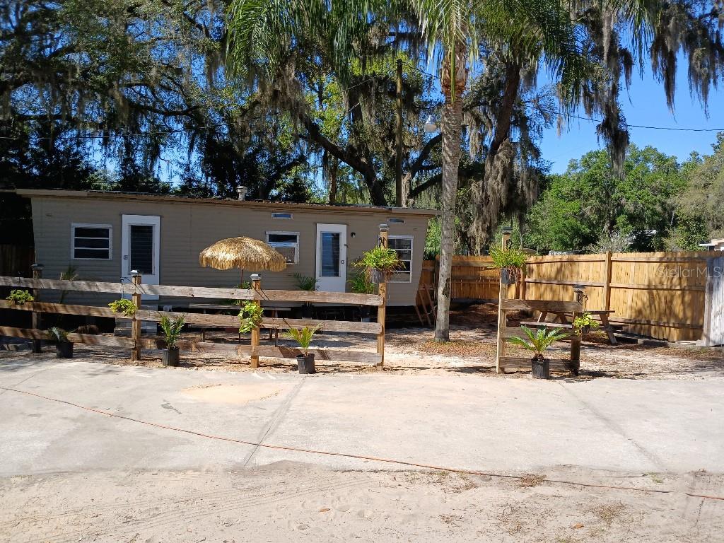 A single-story mobile home sits behind a wooden fence with a concrete driveway in front — 16975 SE 249TH AVENUE, UMATILLA, FL