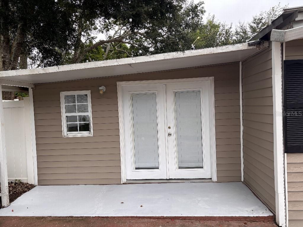 A tan-sided exterior wall features a single window and white double doors under a patio — 16975 SE 249TH AVENUE, UMATILLA, FL