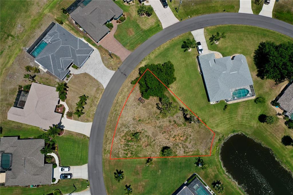 An aerial view shows a vacant, triangular-shaped residential lot bordered by a curved road — 23 MEDALIST CIRCLE, ROTONDA WEST, FL