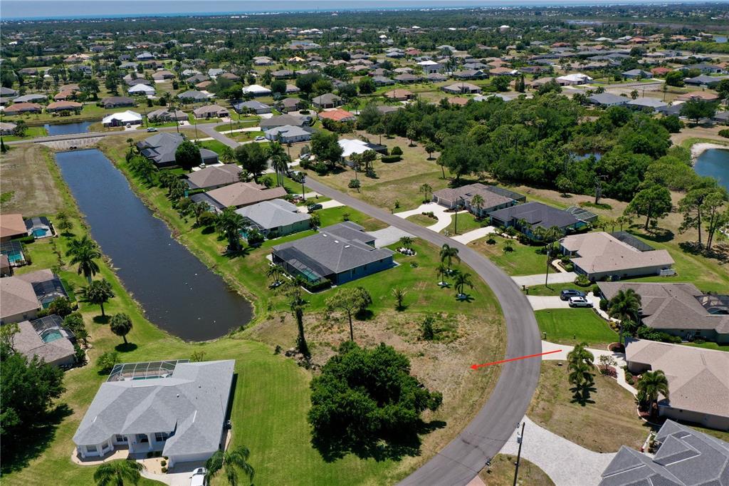 An aerial view shows a vacant residential lot situated between houses and a canal — 23 MEDALIST CIRCLE, ROTONDA WEST, FL