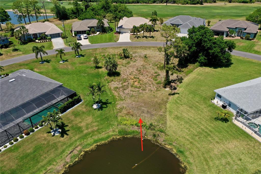 An aerial view shows a vacant residential lot situated between two houses and a pond — 23 MEDALIST CIRCLE, ROTONDA WEST, FL