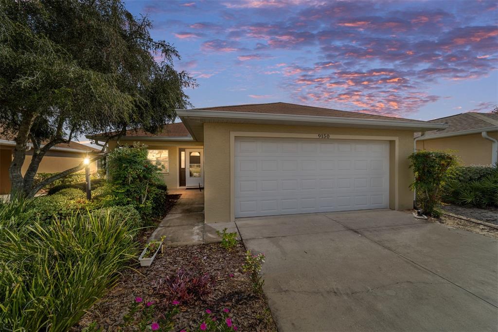 A single-story house with a two-car garage and a concrete driveway at sunset — 9150 SW 102ND CIRCLE, OCALA, FL