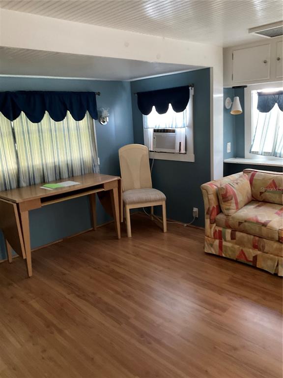 A room with blue walls, wood-look flooring, a desk, a chair, and a patterned sofa — 71 BULL BAY LANE UNIT 71, ENGLEWOOD, FL