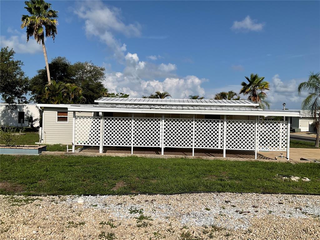 A mobile home features a large covered patio enclosed by white lattice panels — 71 BULL BAY LANE UNIT 71, ENGLEWOOD, FL