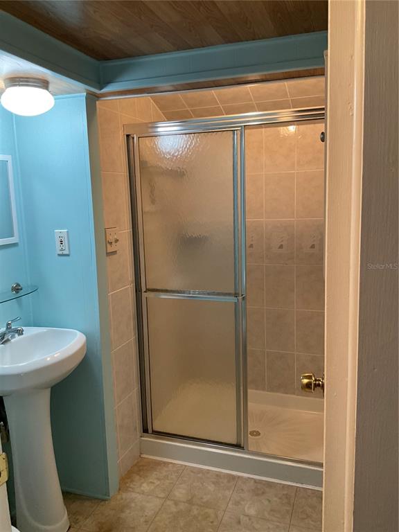 A bathroom features a pedestal sink, light blue walls, and a tiled walk-in shower — 71 BULL BAY LANE UNIT 71, ENGLEWOOD, FL