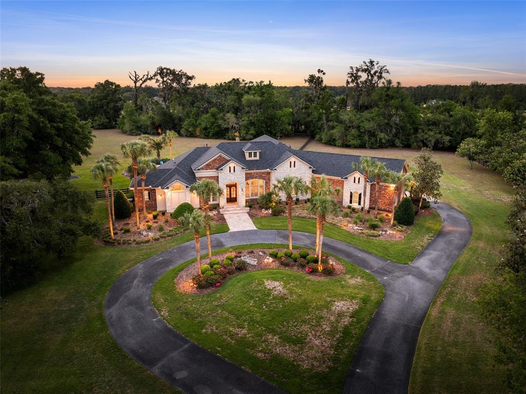 An aerial view of a stone and brick house with a circular driveway and palm trees — 15508 NW 45TH PLACE, NEWBERRY, FL
