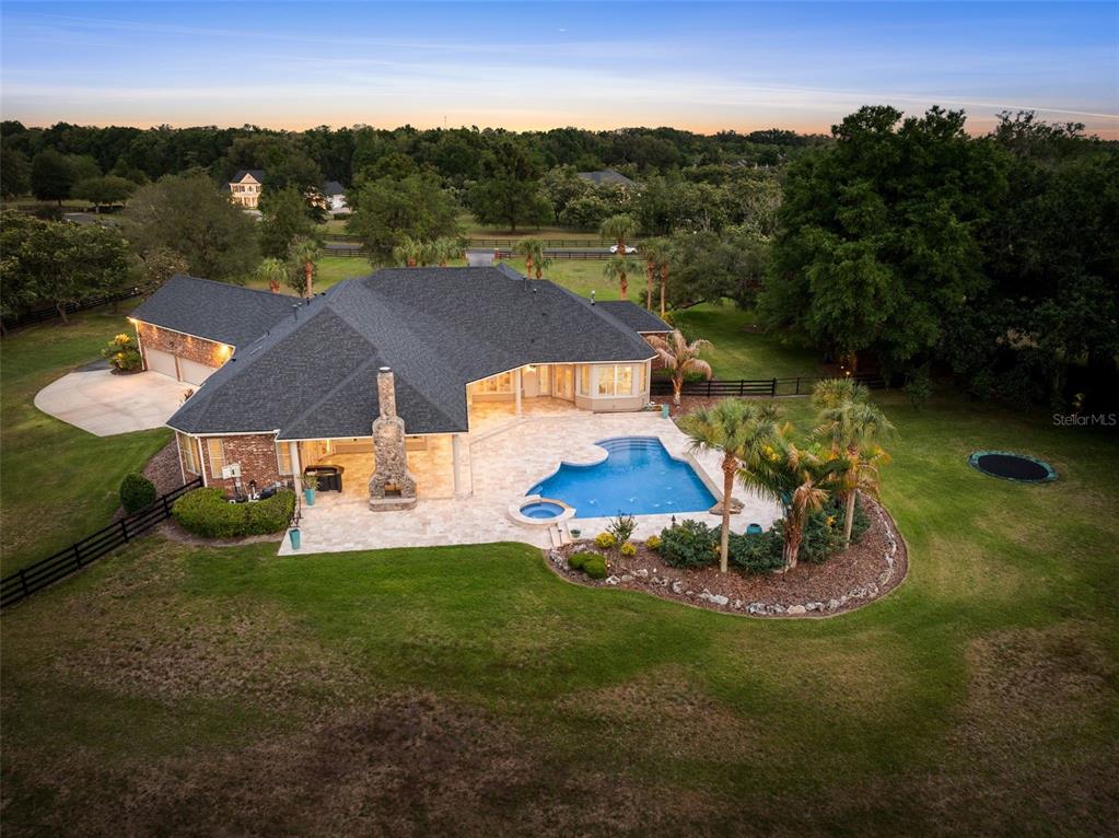 An aerial view of a house with a stone fireplace, swimming pool, and large lawn — 15508 NW 45TH PLACE, NEWBERRY, FL