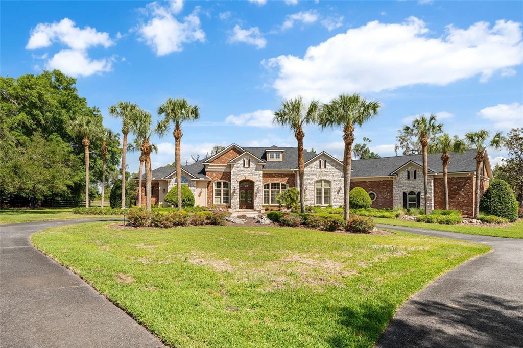 A single-story brick and stone house with a circular driveway and palm trees — 15508 NW 45TH PLACE, NEWBERRY, FL