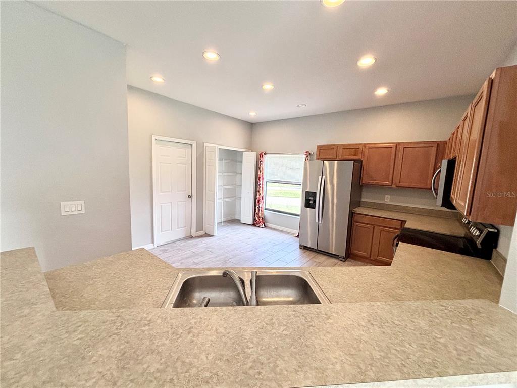 A kitchen features wood cabinets, stainless steel appliances, a double sink, and a pantry closet — 126 SANDY POINT WAY, CLERMONT, FL
