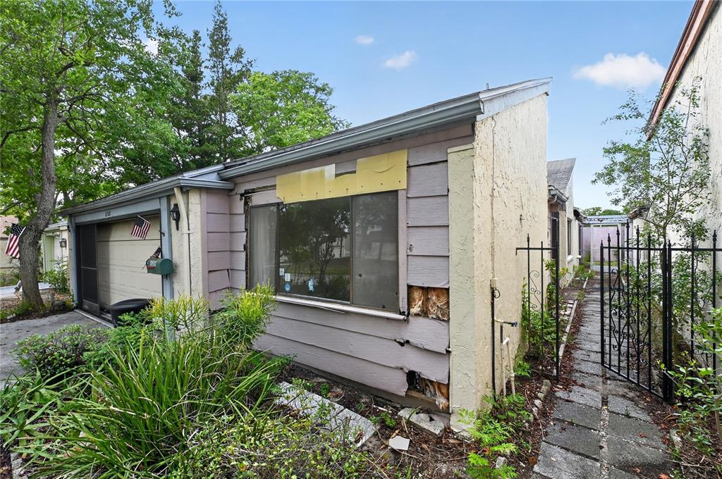 The exterior of a house shows a garage, a window, and damaged siding — 12521 MERRY LANE, HUDSON, FL