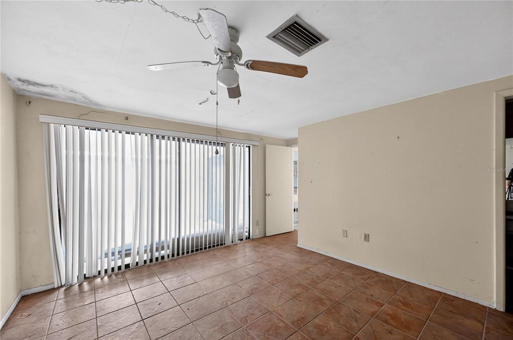 A room with tiled floors, a ceiling fan, and a large window with vertical blinds — 12521 MERRY LANE, HUDSON, FL