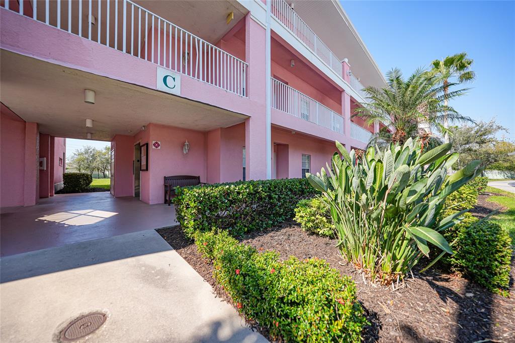 A pink multi-story apartment building exterior features a covered walkway and landscaped garden area — 2061 WILLOW HAMMOCK CIRCLE UNIT 105, PUNTA GORDA, FL