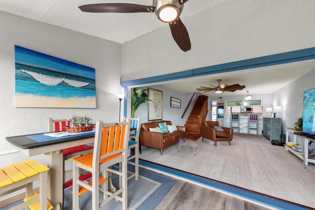 A dining area on a patio opens into a living room with stairs and kitchen — 9434 TARA CAY COURT UNIT 25, SEMINOLE, FL