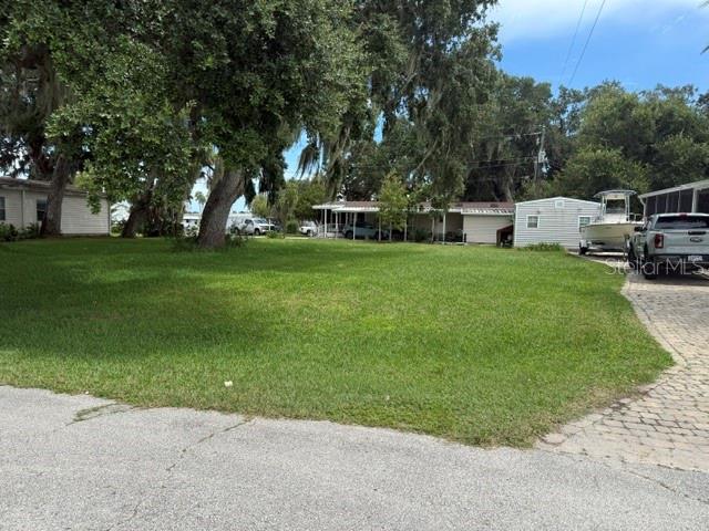 A grassy vacant lot sits in front of a house with a boat parked nearby — 156 RED BASS LANE, EDGEWATER, FL