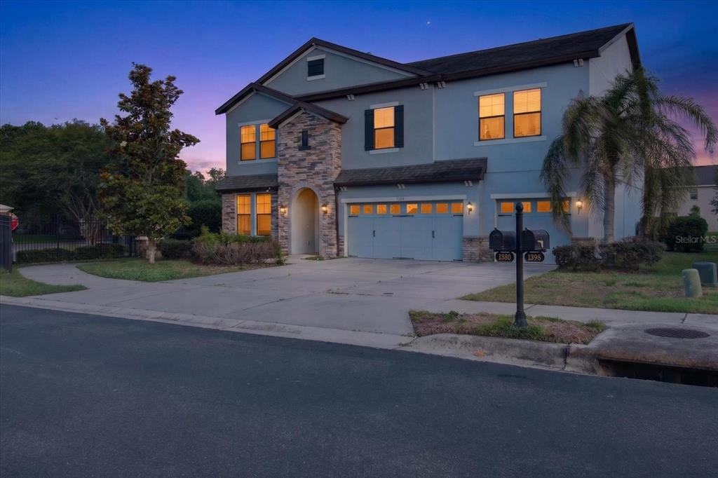 A two-story house with a stone-accented entryway and a three-car garage at dusk — 1389 HERITAGE LANDINGS DRIVE, LAKELAND, FL