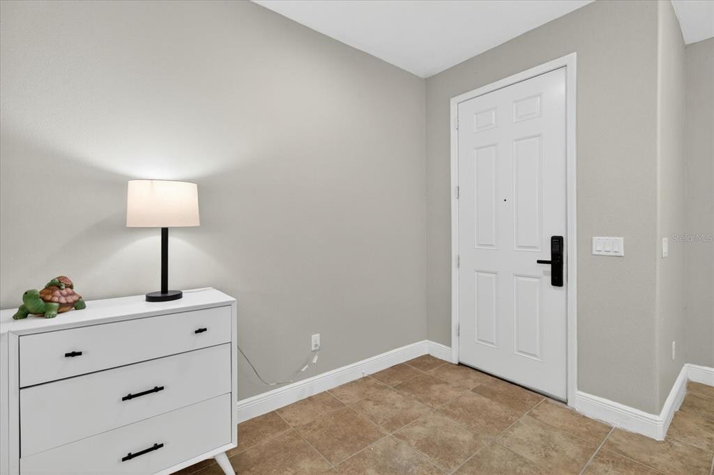 A white dresser with a lamp sits in a tiled entryway near a white door — 1389 HERITAGE LANDINGS DRIVE, LAKELAND, FL