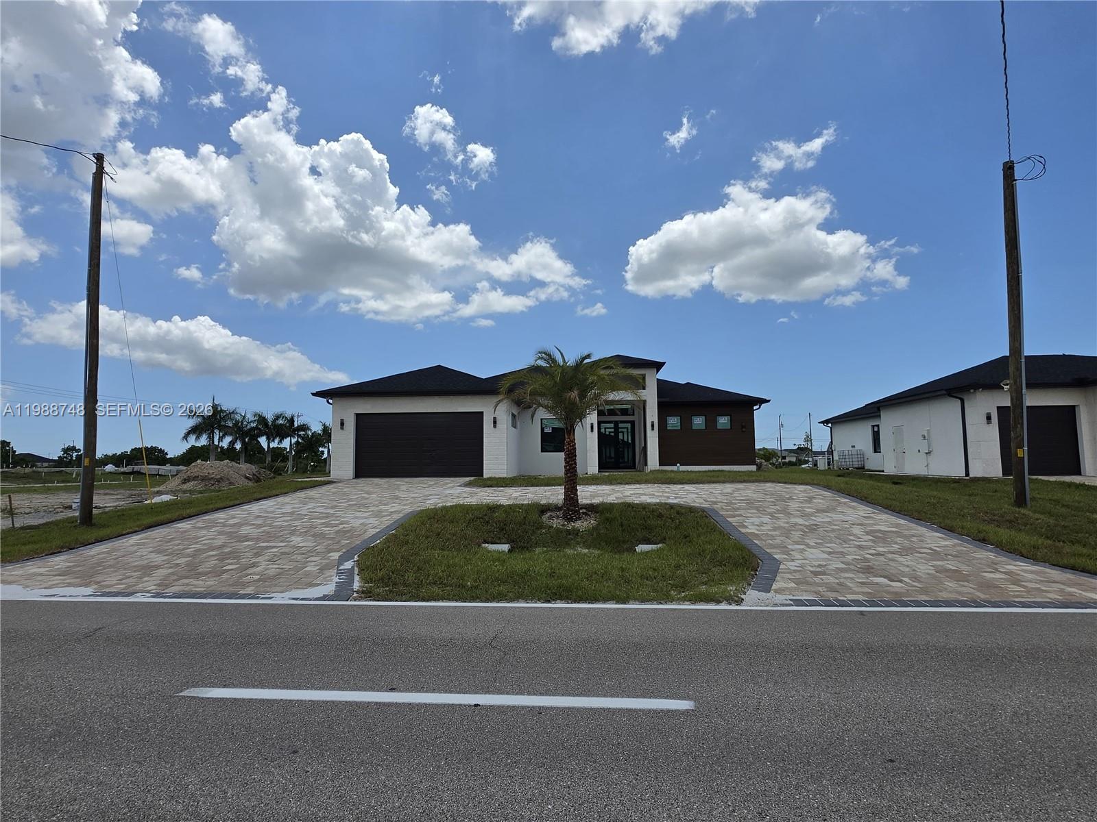 A modern single-story house with a paved driveway and a central palm tree — 2006 Nelson RD N, Cape Coral FL 33993, CAPE CORAL, FL