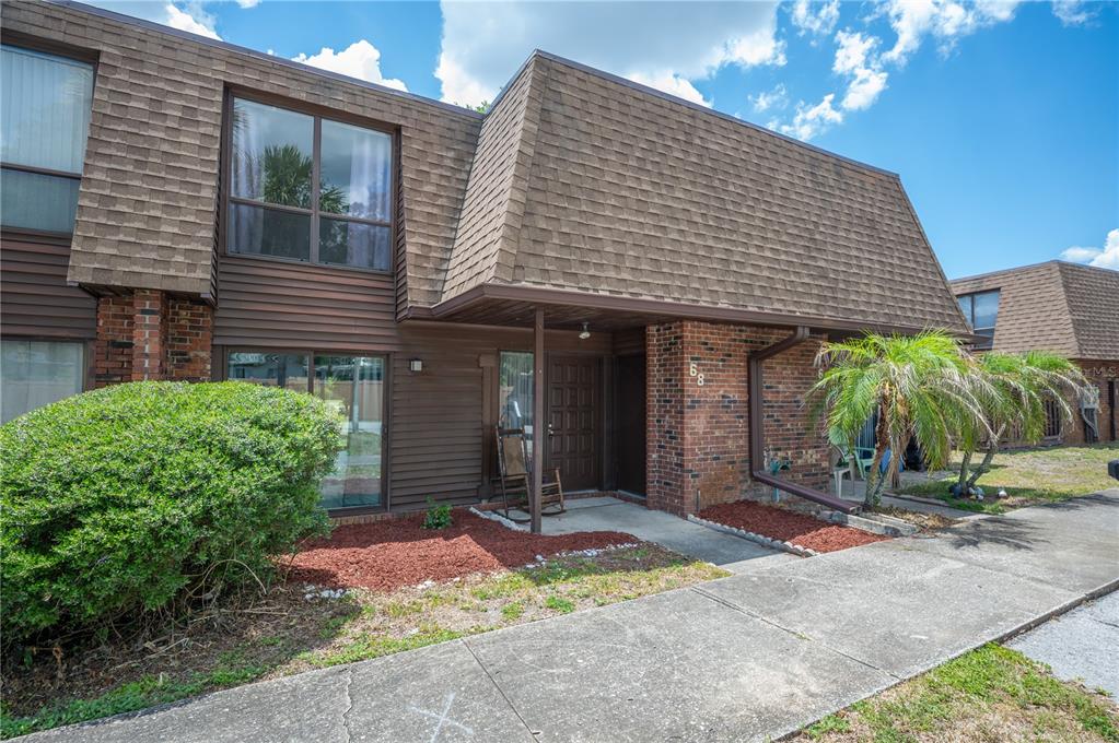 A two-story townhouse exterior with a brown mansard roof, brick facade, and a front porch — 1836 N CRYSTAL LAKE DRIVE UNIT 68, LAKELAND, FL