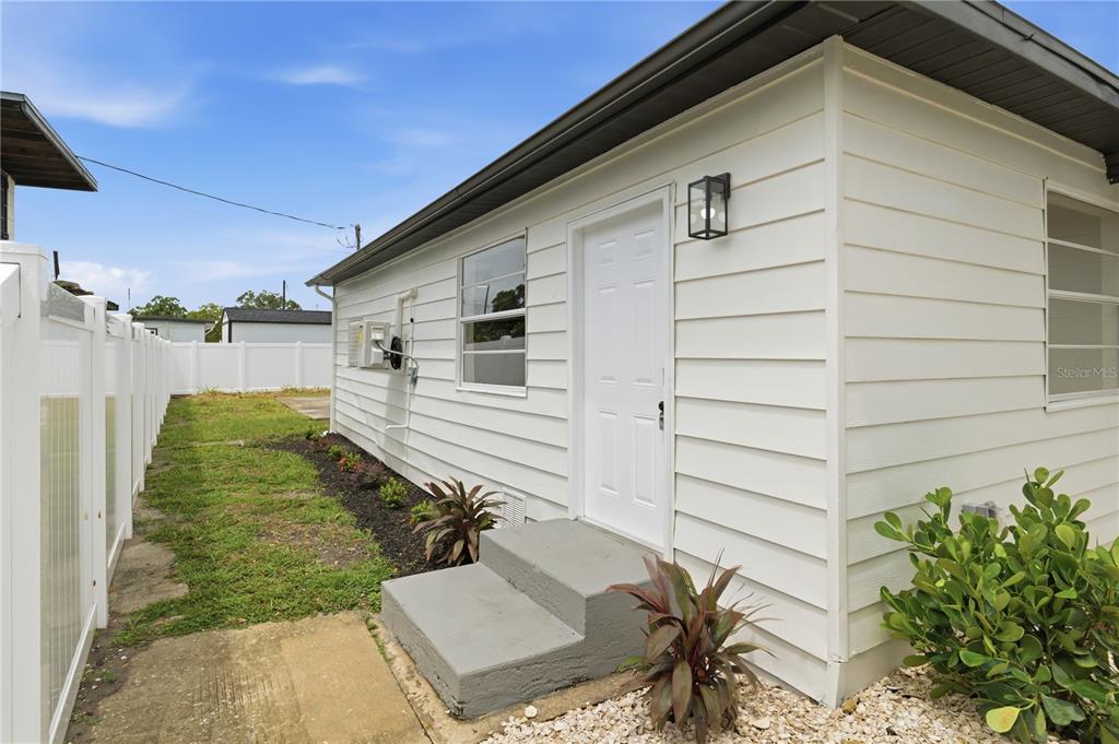 The exterior of a white house features a side door, concrete steps, and landscaping — 3923 W FLORA STREET, TAMPA, FL