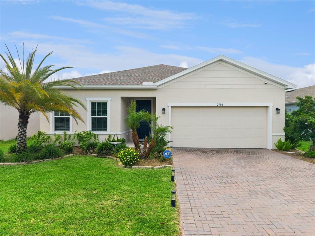 A single-story house with a beige stucco exterior, a two-car garage, and a palm tree — 2106 HAVASU FALLS DRIVE, DELAND, FL